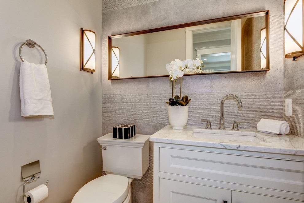 Idéer för mellanstora amerikanska toaletter, med luckor med upphöjd panel, vita skåp, en toalettstol med separat cisternkåpa, grå kakel, keramikplattor, grå väggar, marmorgolv, ett undermonterad handfat, marmorbänkskiva och vitt golv