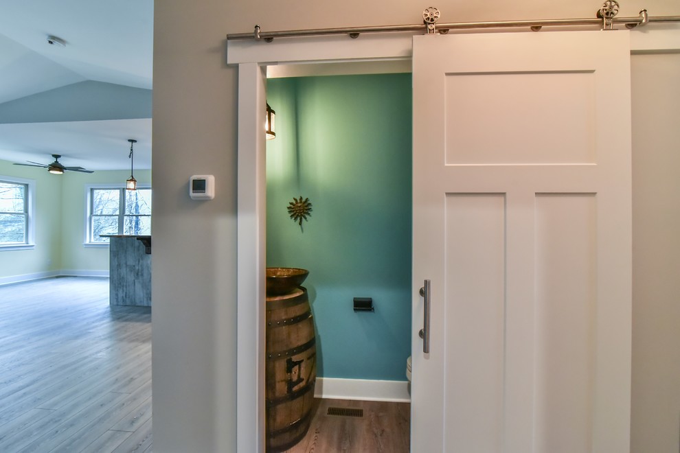 Exemple d'un petit WC et toilettes craftsman avec un placard en trompe-l'oeil, WC séparés, un mur bleu, parquet clair, une vasque, un plan de toilette en bois, un sol marron et un plan de toilette marron.