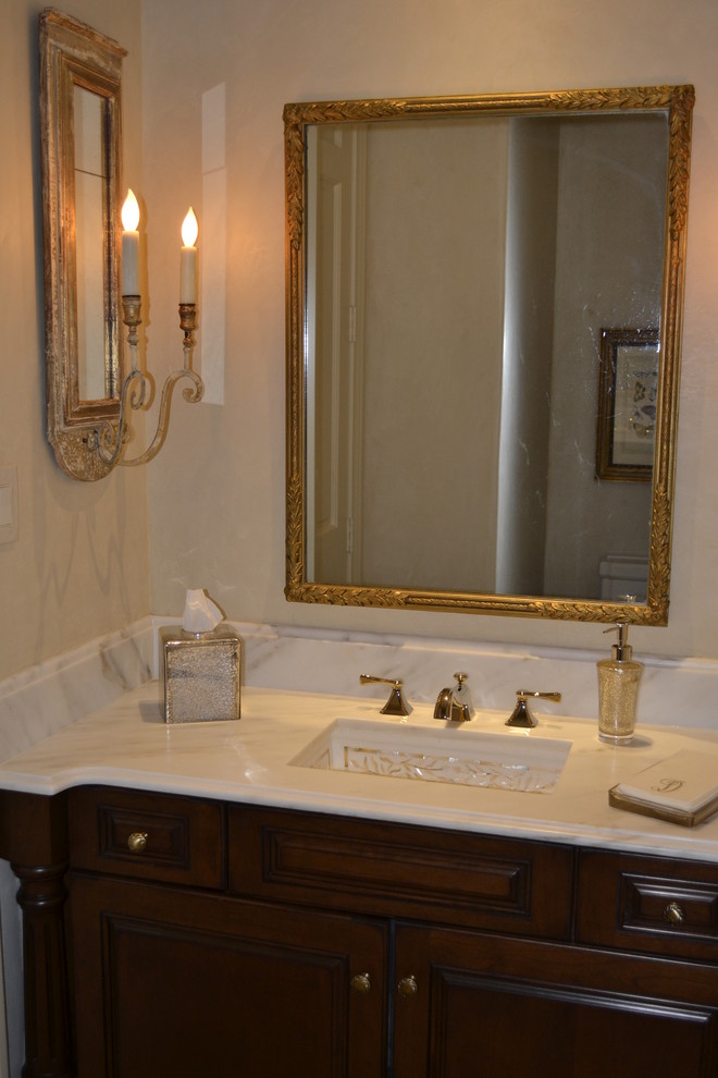 Immagine di un grande bagno di servizio tradizionale con ante con bugna sagomata, ante in legno bruno, pareti beige, lavabo sottopiano e top in marmo