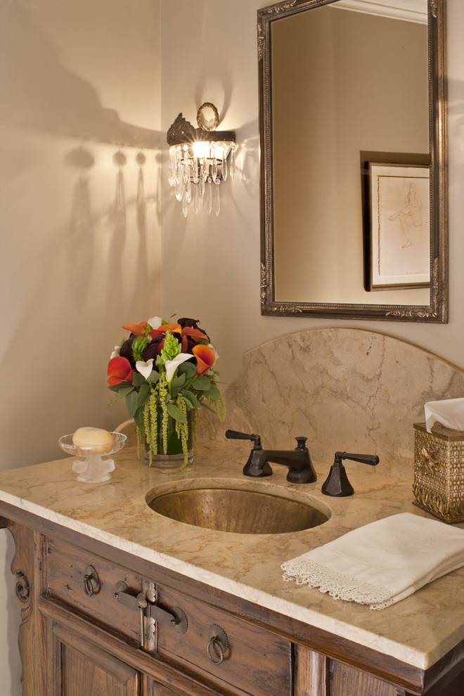 Immagine di un piccolo bagno di servizio stile rurale con lavabo sottopiano, ante con riquadro incassato, ante in legno scuro, pareti beige e top beige