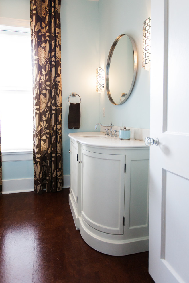 Exemple d'un WC et toilettes chic de taille moyenne avec un lavabo encastré, des portes de placard blanches, un plan de toilette en marbre, un mur bleu et un sol en liège.
