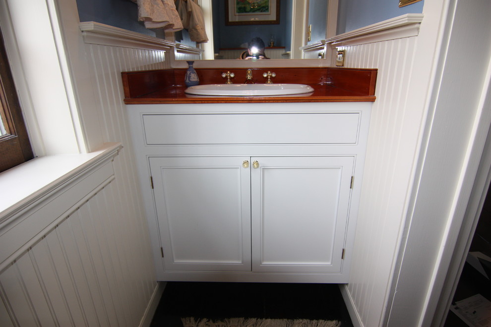 Foto di un piccolo bagno di servizio classico con lavabo da incasso, ante a filo, ante bianche, top in legno, WC monopezzo e pareti blu