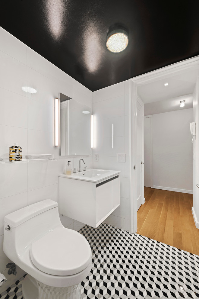 Imagen de aseo moderno pequeño con sanitario de una pieza, baldosas y/o azulejos blancos, paredes blancas, suelo de mármol, lavabo suspendido, armarios con paneles lisos y puertas de armario blancas