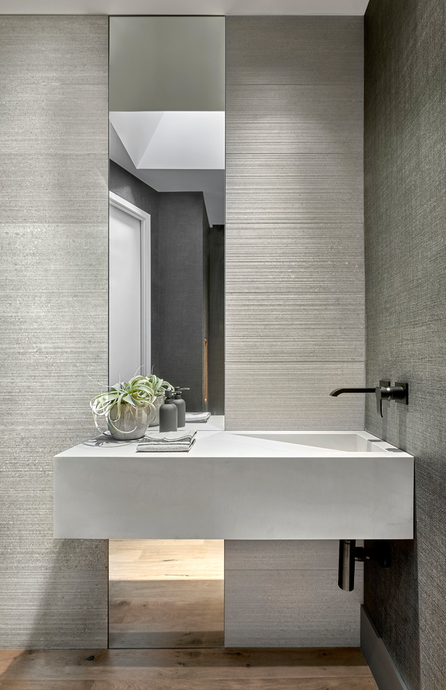 На фото: туалет среднего размера в стиле модернизм с серой плиткой, керамогранитной плиткой, серыми стенами, светлым паркетным полом и монолитной раковиной