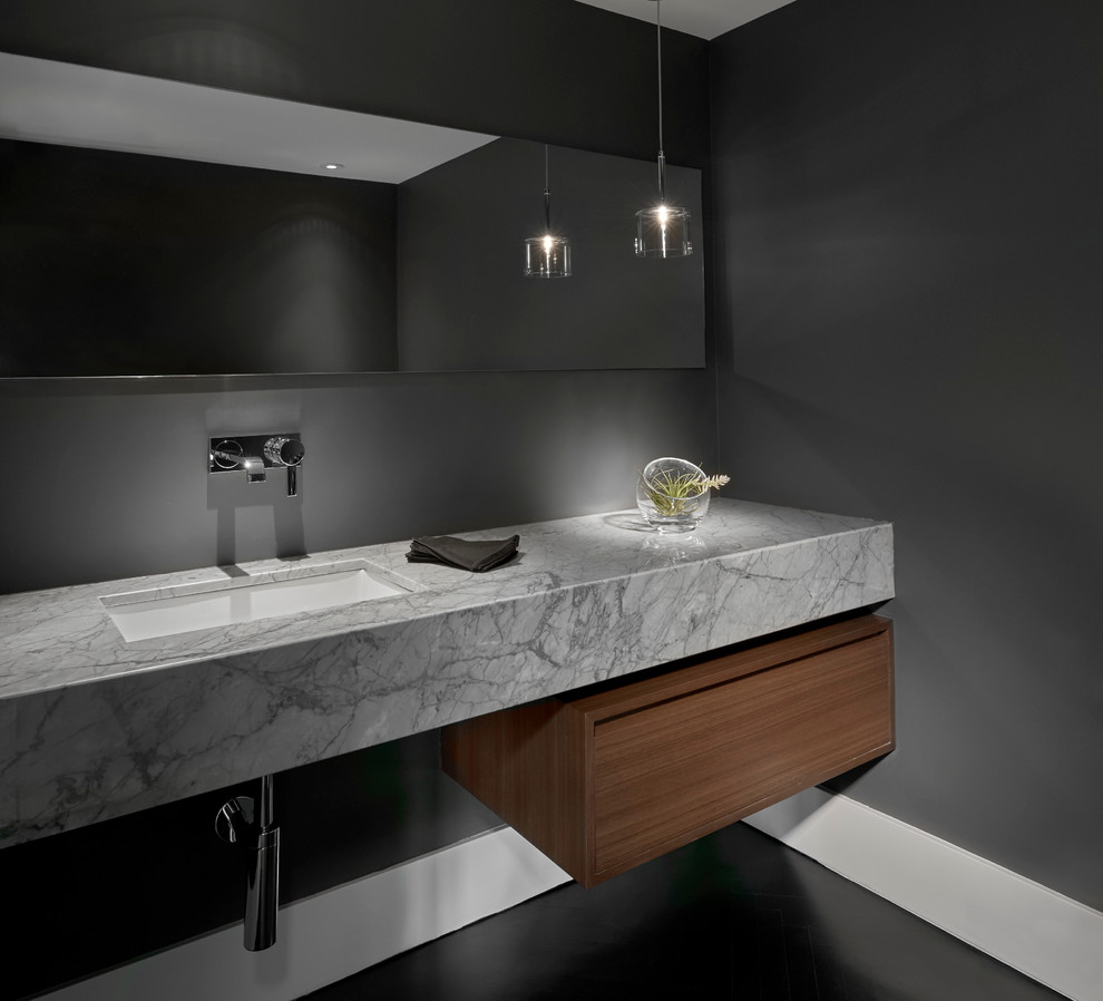 Mittelgroße Moderne Gästetoilette mit flächenbündigen Schrankfronten, grauer Wandfarbe, dunklen Holzschränken, Unterbauwaschbecken und grauer Waschtischplatte in Chicago