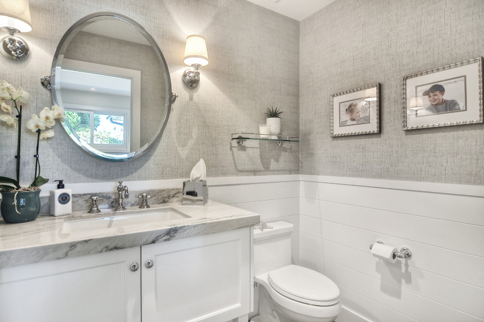 Immagine di un bagno di servizio tradizionale di medie dimensioni con ante con riquadro incassato, ante bianche, WC monopezzo, pareti grigie, lavabo sottopiano e top in granito