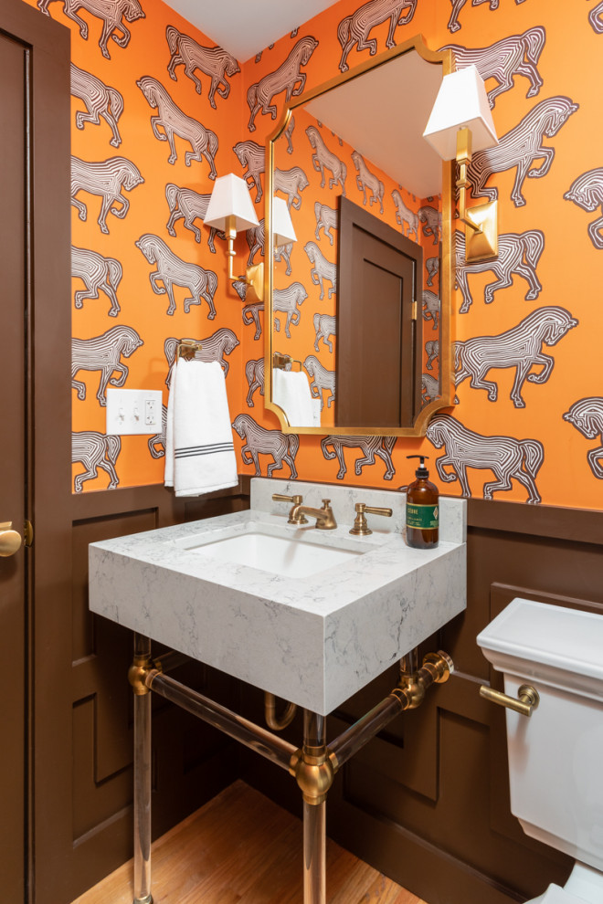 Foto på ett litet vintage vit toalett, med en toalettstol med separat cisternkåpa, orange väggar, mellanmörkt trägolv, ett integrerad handfat, bänkskiva i kvarts och brunt golv