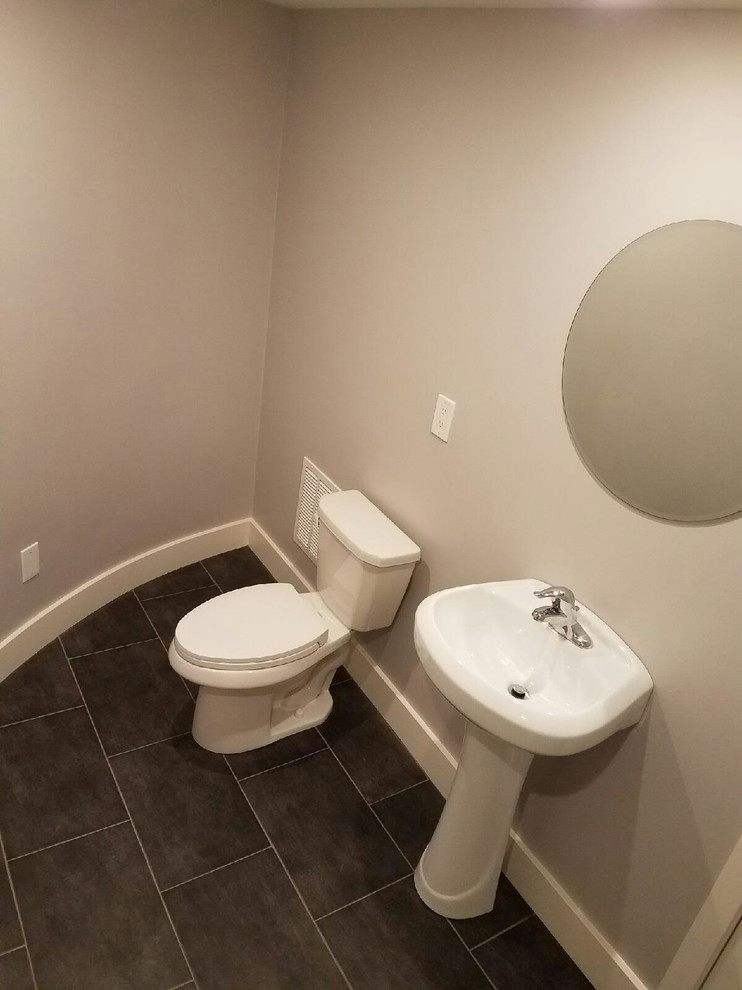 Immagine di un bagno di servizio classico di medie dimensioni con WC a due pezzi, pareti grigie, pavimento in gres porcellanato e lavabo a colonna