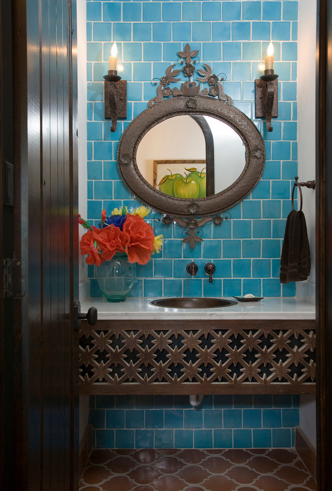 На фото: туалет в средиземноморском стиле с накладной раковиной, синей плиткой, синими стенами и белой столешницей