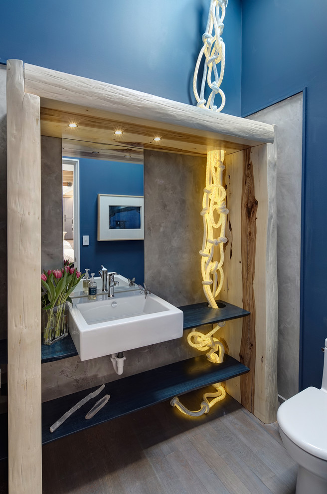 Ejemplo de aseo actual con armarios abiertos, sanitario de una pieza, paredes azules y suelo de madera en tonos medios