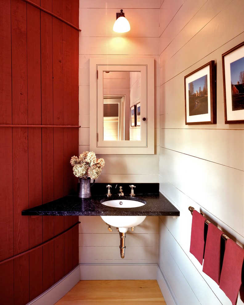 ニューヨークにあるラグジュアリーな広いカントリー風のおしゃれなトイレ・洗面所 (アンダーカウンター洗面器、御影石の洗面台、赤い壁、淡色無垢フローリング) の写真