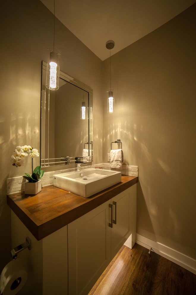Immagine di un bagno di servizio minimal di medie dimensioni con lavabo a bacinella, ante in stile shaker, ante bianche, top in legno, pareti beige, pavimento in legno massello medio e top marrone