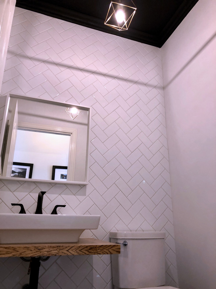 Diseño de aseo contemporáneo pequeño con sanitario de dos piezas, baldosas y/o azulejos blancos, baldosas y/o azulejos de cemento, paredes blancas, lavabo suspendido y encimera de madera