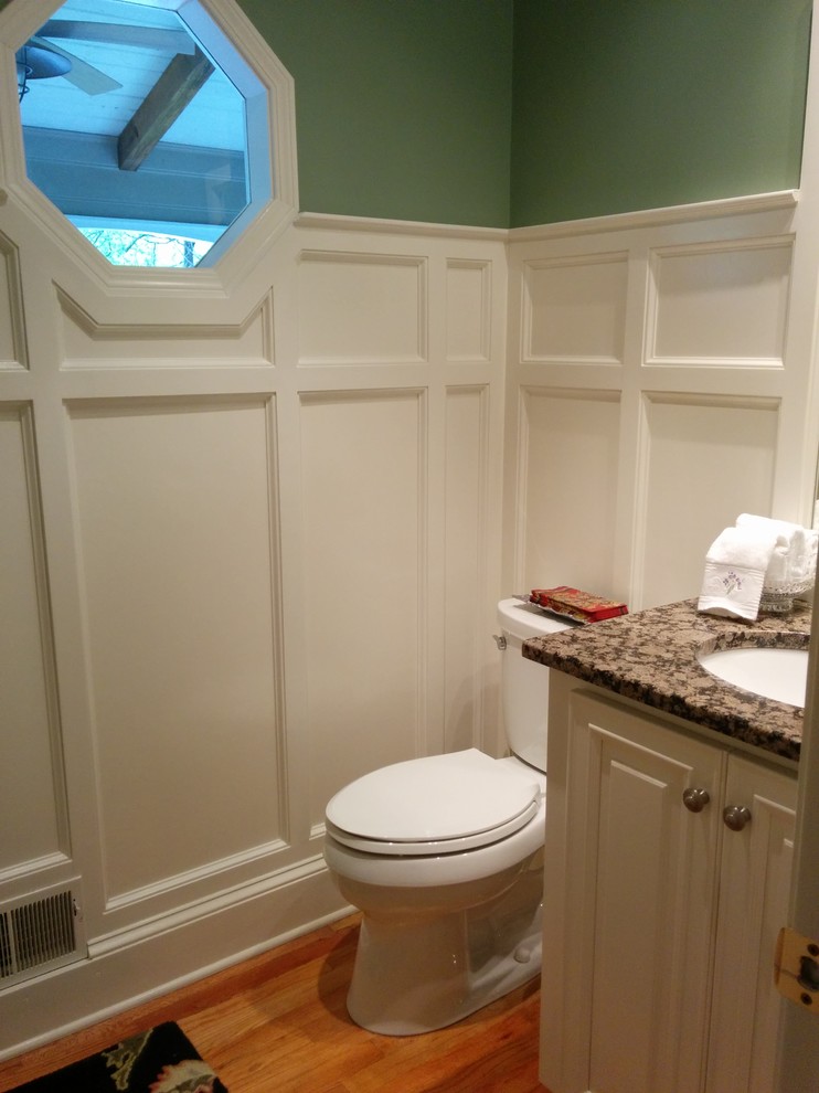 Inspiration pour un WC et toilettes craftsman de taille moyenne avec un placard avec porte à panneau surélevé, des portes de placard beiges, un mur vert, parquet clair et un plan de toilette en granite.