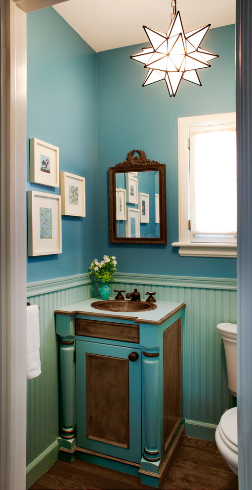 Esempio di un piccolo bagno di servizio tradizionale con lavabo da incasso, consolle stile comò, ante turchesi, top in laminato, pareti blu e pavimento in legno massello medio