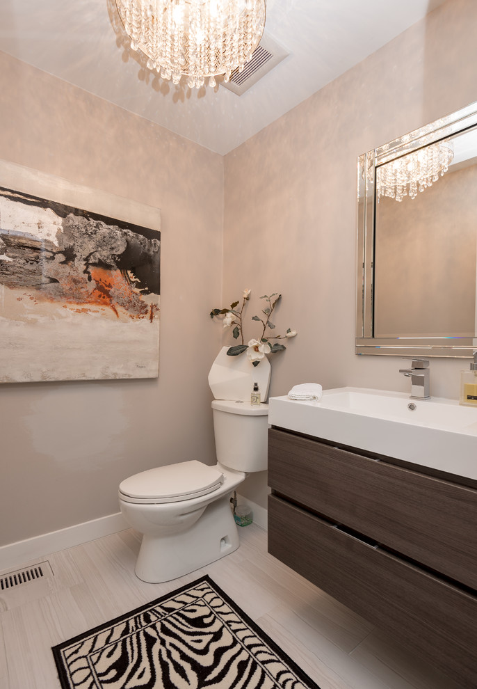 Foto di un bagno di servizio classico di medie dimensioni con ante lisce, ante in legno bruno, pareti beige, pavimento in gres porcellanato, lavabo integrato, top in superficie solida e pavimento beige