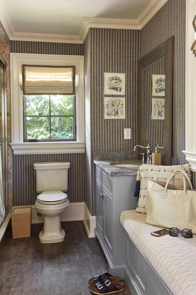 Exemple d'un WC et toilettes bord de mer avec un placard à porte shaker, des portes de placard grises, WC séparés, un mur multicolore, parquet foncé, un lavabo encastré, un sol marron et un plan de toilette gris.