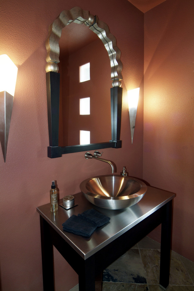 Bild på ett funkis toalett, med ett fristående handfat, svarta skåp, bänkskiva i rostfritt stål och skiffergolv