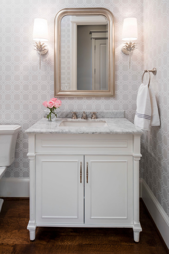 Cette image montre un WC et toilettes traditionnel avec un placard en trompe-l'oeil, des portes de placard blanches, WC séparés, un mur gris, parquet foncé, un lavabo encastré et un plan de toilette en marbre.