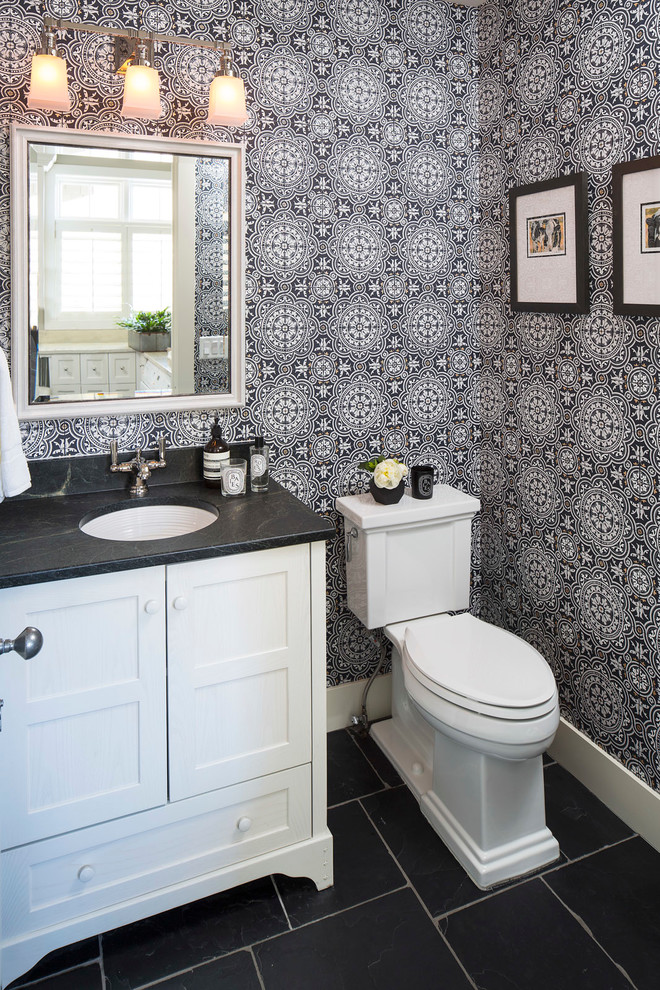 Foto di un bagno di servizio tradizionale con consolle stile comò, ante bianche, WC a due pezzi, pareti multicolore, lavabo sottopiano, pavimento nero e top nero