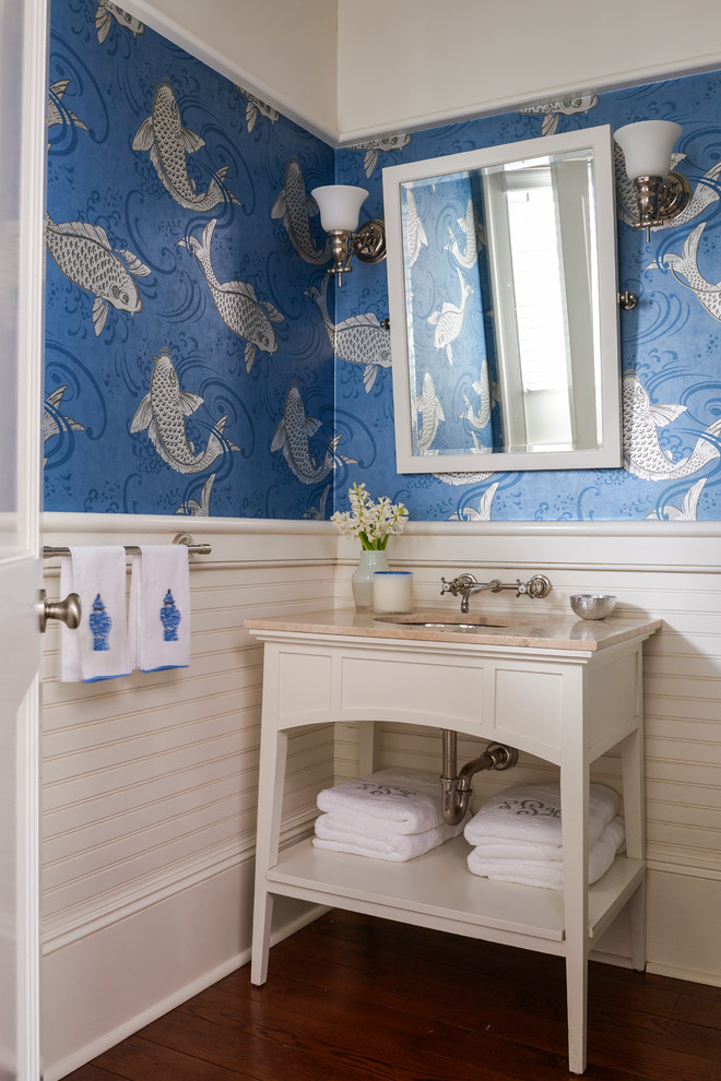 Klassisk inredning av ett mellanstort toalett, med ett undermonterad handfat, öppna hyllor, vita skåp, bänkskiva i kalksten, blå väggar och mellanmörkt trägolv