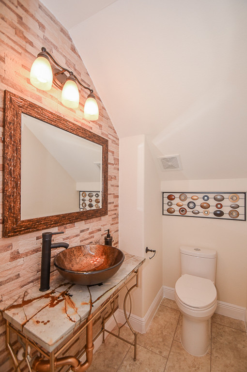 Inspiration for a small classic cloakroom in Houston with a one-piece toilet, brown tiles, porcelain tiles, beige walls, porcelain flooring, a vessel sink and quartz worktops.