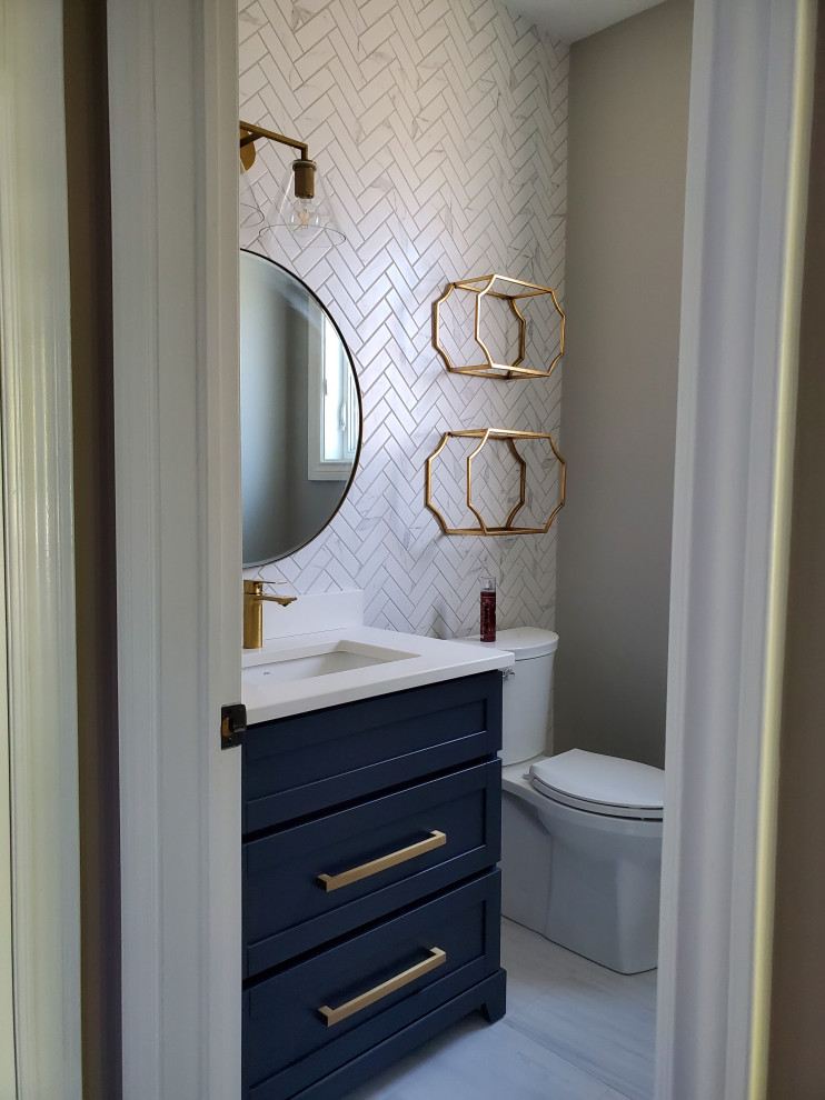 Medium sized modern cloakroom in Toronto with shaker cabinets, blue cabinets, quartz worktops, white worktops, a built in vanity unit, a two-piece toilet, white tiles, metro tiles, white walls, vinyl flooring, a submerged sink, multi-coloured floors, a feature wall and a vaulted ceiling.