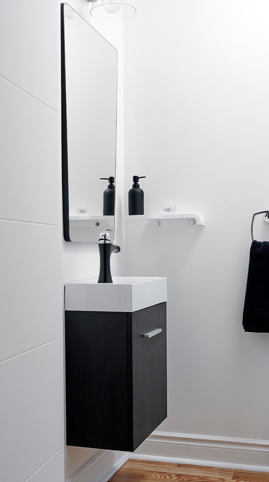 Kleine Moderne Gästetoilette mit flächenbündigen Schrankfronten, schwarzen Schränken, weißer Wandfarbe, braunem Holzboden, integriertem Waschbecken, Quarzit-Waschtisch und braunem Boden in Toronto