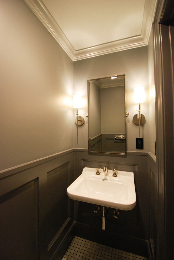 Klassisk inredning av ett litet toalett, med en vägghängd toalettstol, grå väggar, mosaikgolv, ett väggmonterat handfat, flerfärgat golv, vita skåp och marmorkakel