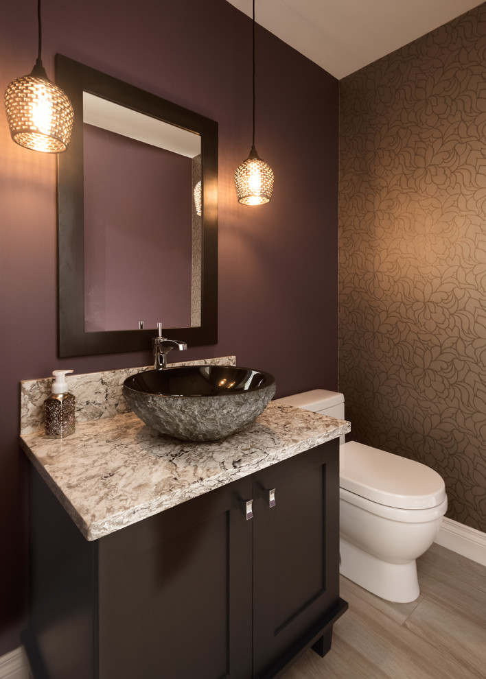 Cette image montre un WC et toilettes design en bois foncé de taille moyenne avec une vasque, un placard avec porte à panneau encastré, un plan de toilette en quartz modifié, WC à poser, un mur violet et un sol en carrelage de porcelaine.
