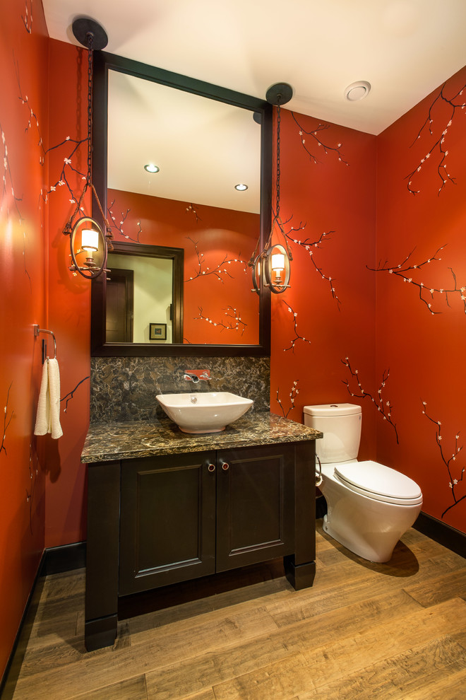 Urige Gästetoilette mit Aufsatzwaschbecken, Schrankfronten mit vertiefter Füllung, dunklen Holzschränken, Quarzwerkstein-Waschtisch, Toilette mit Aufsatzspülkasten, roter Wandfarbe und braunem Holzboden in Vancouver