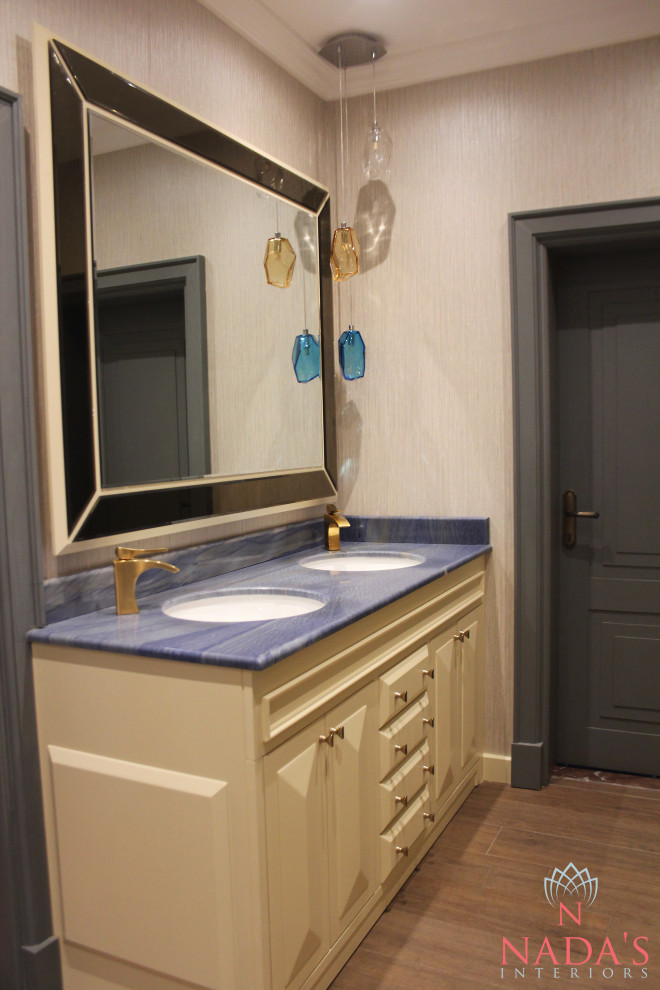 Foto på ett mellanstort funkis blå toalett, med luckor med upphöjd panel, beige skåp, beige väggar, ett undermonterad handfat, marmorbänkskiva och brunt golv