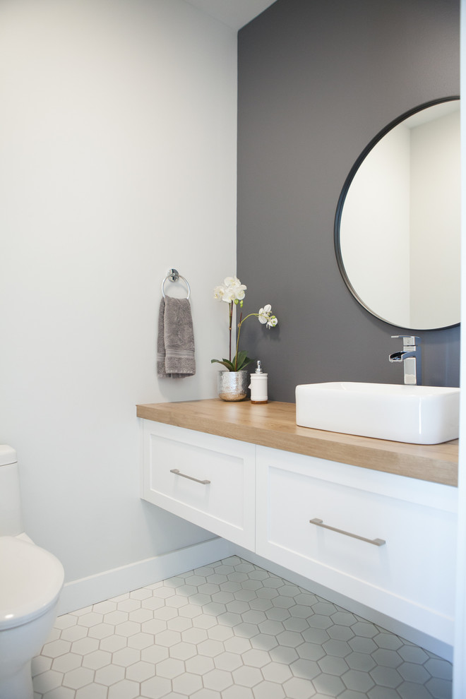 Cette image montre un petit WC et toilettes minimaliste avec un placard à porte shaker, des portes de placard blanches, un sol en carrelage de céramique, une vasque, un plan de toilette en stratifié et un sol blanc.