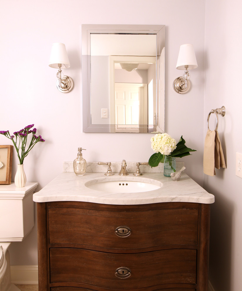 Cette image montre un petit WC et toilettes traditionnel en bois brun avec un lavabo encastré, un placard en trompe-l'oeil, un plan de toilette en marbre, WC séparés, un mur bleu, un sol en carrelage de porcelaine et un sol beige.