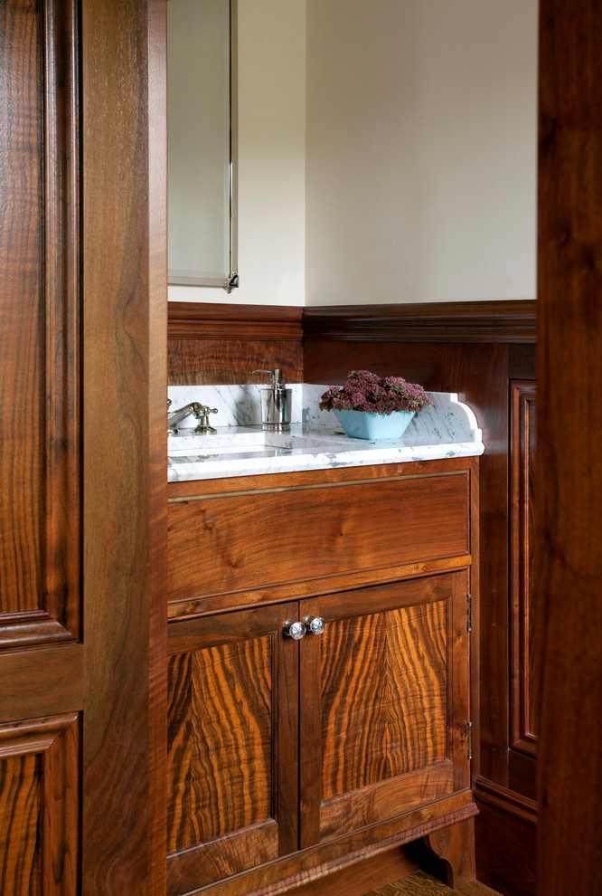 Exempel på ett toalett, med luckor med infälld panel, skåp i mellenmörkt trä, vita väggar, ljust trägolv, ett nedsänkt handfat och marmorbänkskiva