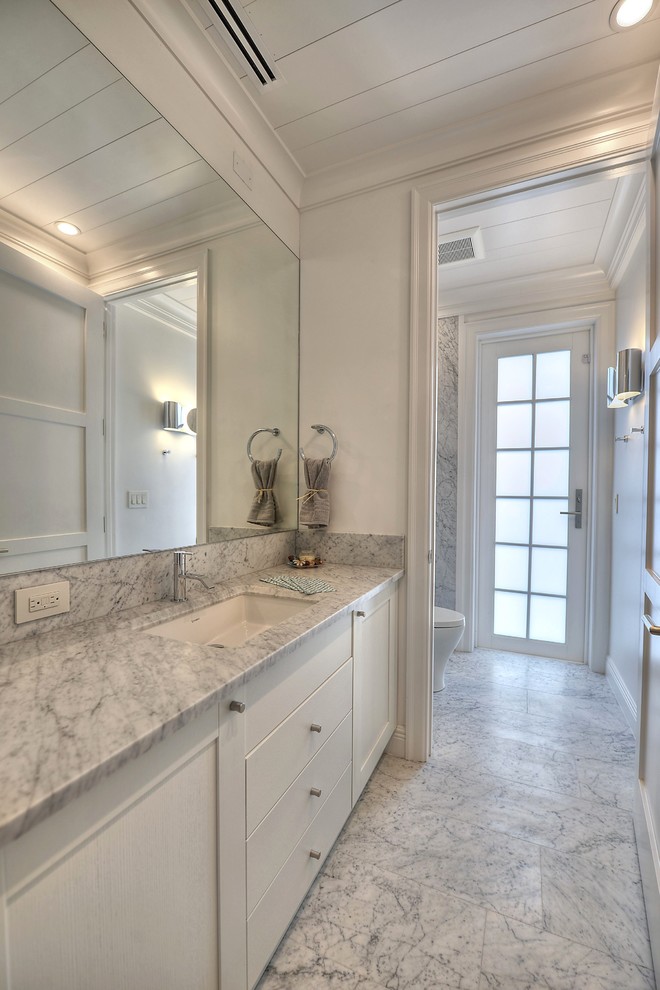 Idées déco pour un WC et toilettes contemporain de taille moyenne avec des portes de placard blanches, un plan de toilette en marbre, un mur blanc, un sol en marbre, du carrelage en marbre et un plan de toilette gris.