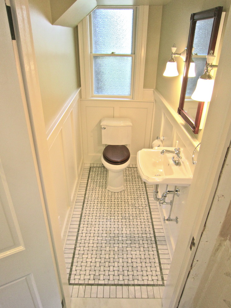 Foto på ett litet vintage toalett, med ett väggmonterat handfat, en toalettstol med separat cisternkåpa och grå kakel