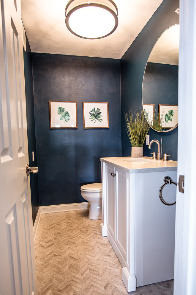 Inredning av ett modernt litet toalett, med möbel-liknande, vita skåp, en toalettstol med hel cisternkåpa, blå väggar, klinkergolv i keramik, ett undermonterad handfat, bänkskiva i kvartsit och flerfärgat golv