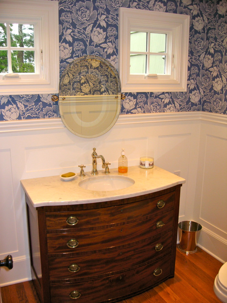 Klassisk inredning av ett litet toalett, med ett undermonterad handfat, möbel-liknande, skåp i mörkt trä, marmorbänkskiva, blå väggar och mellanmörkt trägolv