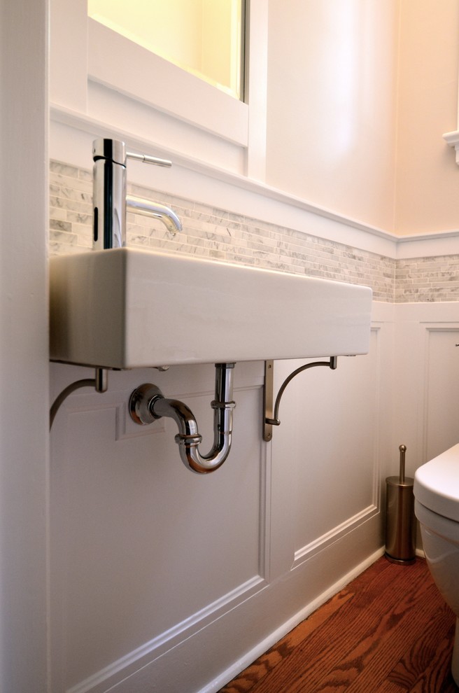 Bild på ett litet vintage toalett, med grå kakel, stenkakel, vita väggar, mellanmörkt trägolv och ett väggmonterat handfat