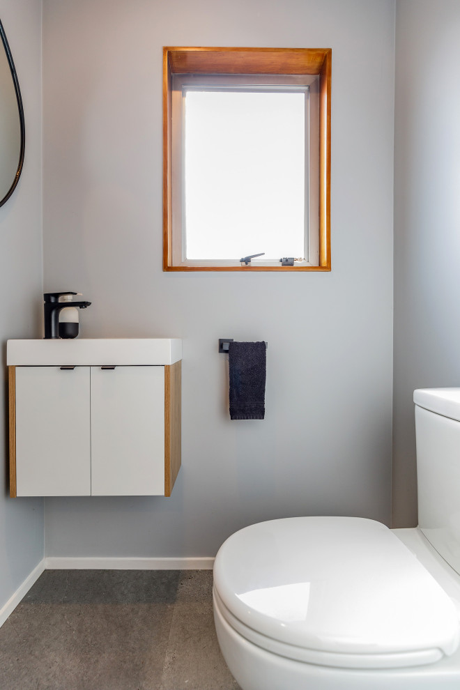 Inspiration for a small contemporary cloakroom in Auckland with freestanding cabinets, white cabinets, a one-piece toilet, grey walls, lino flooring, a built-in sink, grey floors, white worktops and a floating vanity unit.