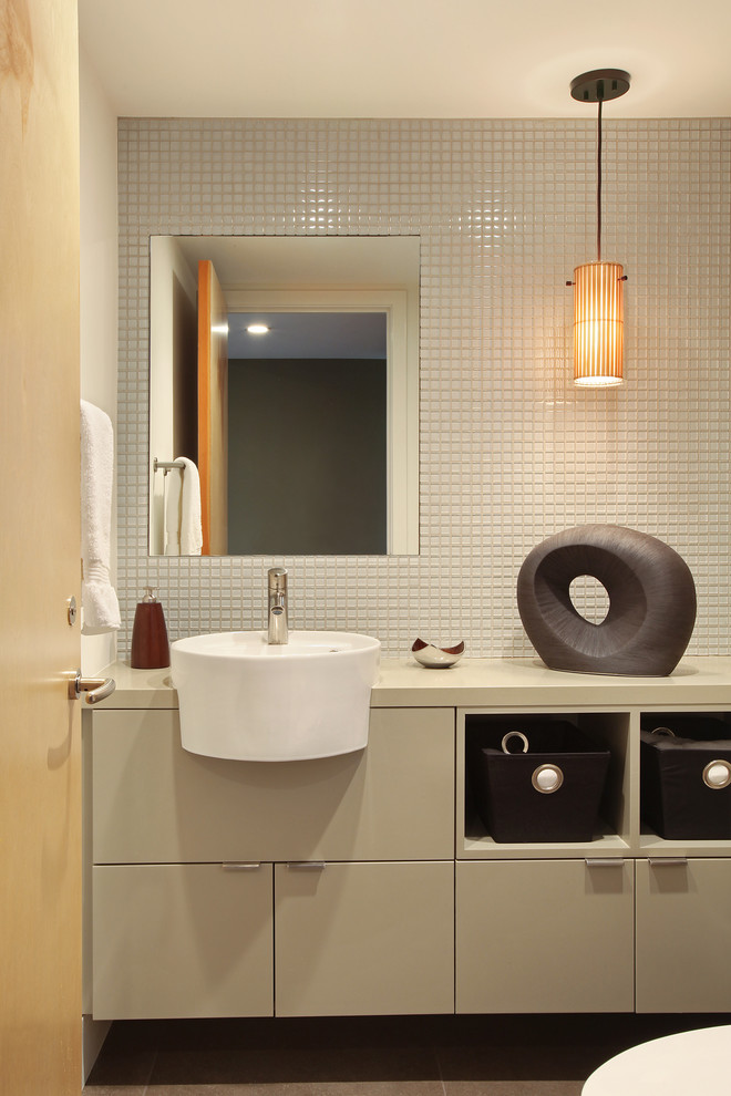 На фото: маленький туалет в стиле модернизм с серыми фасадами, белой плиткой, стеклянной плиткой, белыми стенами, монолитной раковиной, столешницей из искусственного кварца, плоскими фасадами и серым полом для на участке и в саду с