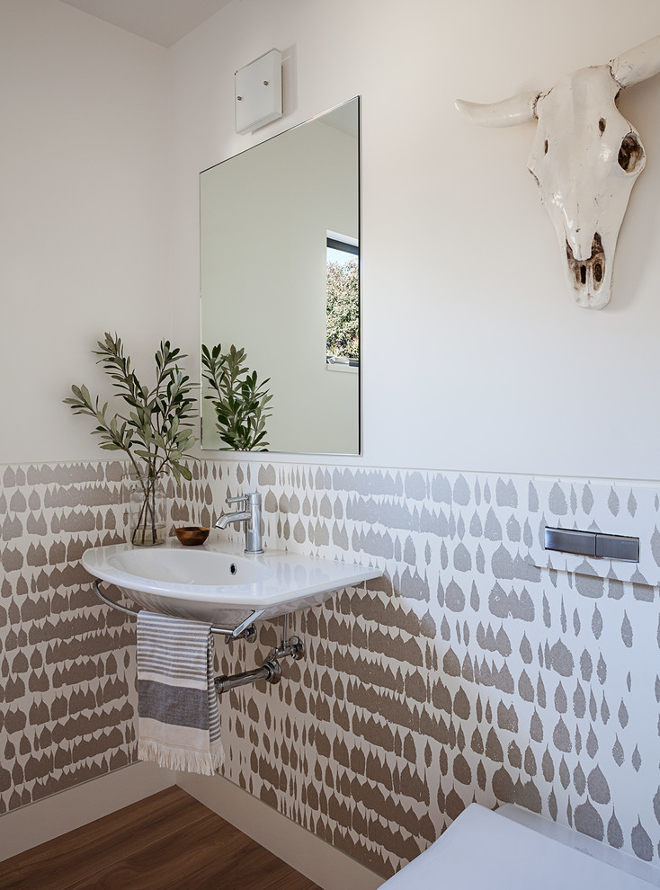 Imagen de aseo contemporáneo pequeño con sanitario de pared, paredes blancas, suelo de madera clara y lavabo suspendido