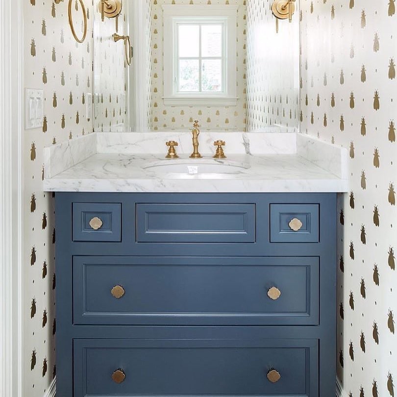 Inredning av ett klassiskt litet toalett, med luckor med infälld panel, blå skåp, en toalettstol med hel cisternkåpa, vita väggar, ett undermonterad handfat och marmorbänkskiva