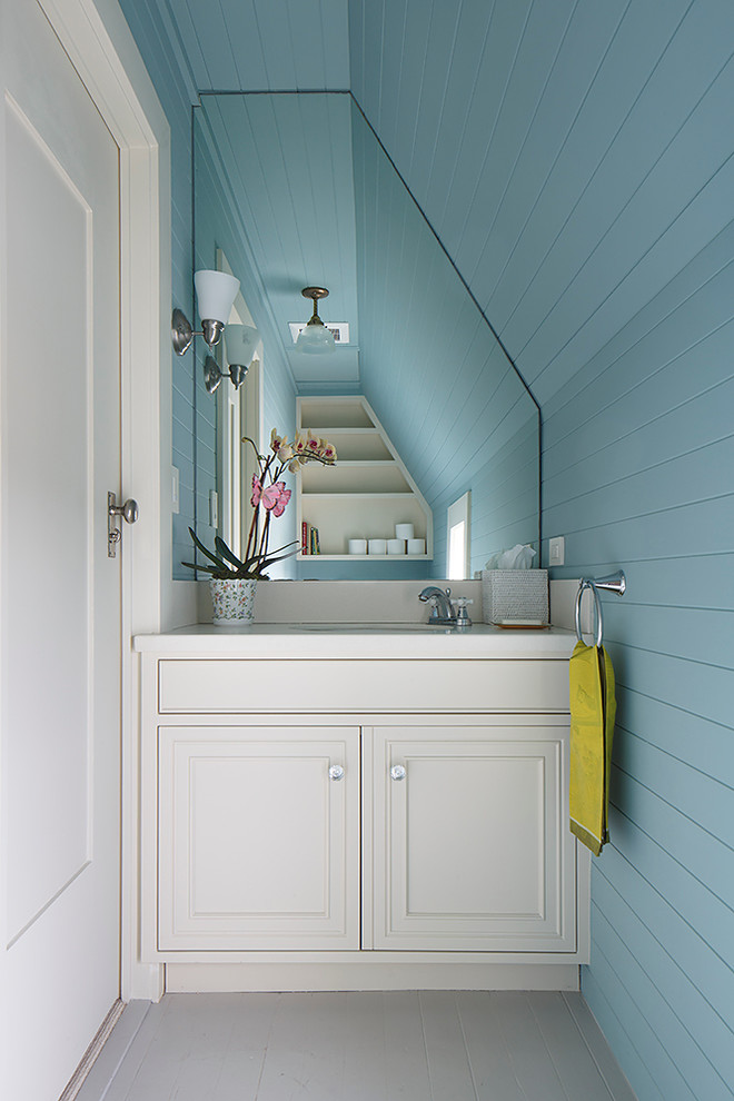 Idee per un piccolo bagno di servizio classico con lavabo sottopiano, ante a filo, ante bianche, top in superficie solida, pareti blu e pavimento in legno verniciato