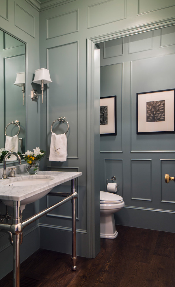 Exempel på ett stort klassiskt vit vitt toalett, med öppna hyllor, en toalettstol med hel cisternkåpa, blå väggar, mörkt trägolv, ett konsol handfat, marmorbänkskiva och brunt golv