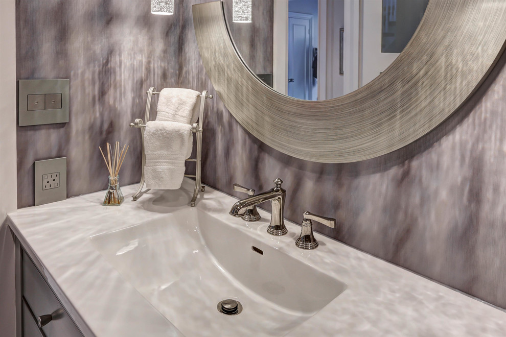 Idee per un bagno di servizio minimal di medie dimensioni con ante lisce, ante grigie, WC a due pezzi, pareti viola, pavimento in marmo, lavabo da incasso, top in superficie solida e pavimento bianco