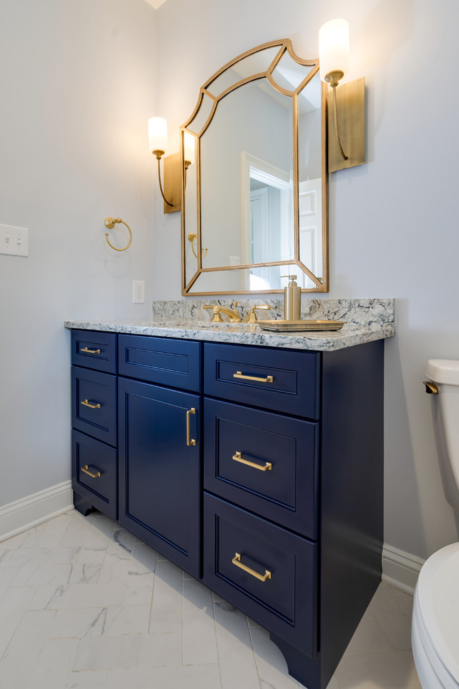 Inredning av ett klassiskt mellanstort toalett, med luckor med infälld panel, blå skåp, en toalettstol med separat cisternkåpa, blå väggar, klinkergolv i porslin, ett undermonterad handfat, bänkskiva i kvarts och vitt golv