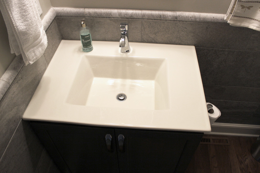 Esempio di un piccolo bagno di servizio chic con ante lisce, ante grigie, WC a due pezzi, pareti beige, pavimento in legno massello medio, lavabo da incasso, top in superficie solida, pavimento marrone e top bianco