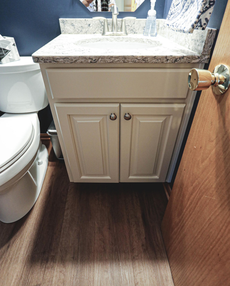 Klassisk inredning av ett litet beige beige toalett, med luckor med upphöjd panel, en toalettstol med separat cisternkåpa, blå väggar, vinylgolv, ett undermonterad handfat och bänkskiva i kvarts